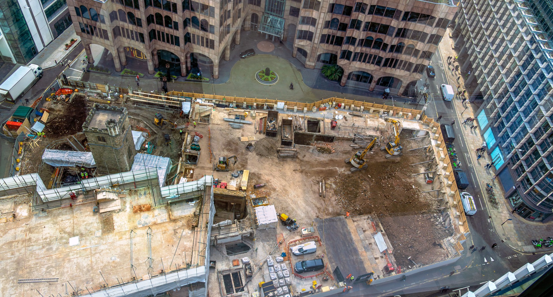 Aerial view of a construction site and building site with heavy machinery in operation in London's city centre financial district. Urban excavations in a commercial area preserving historic building.